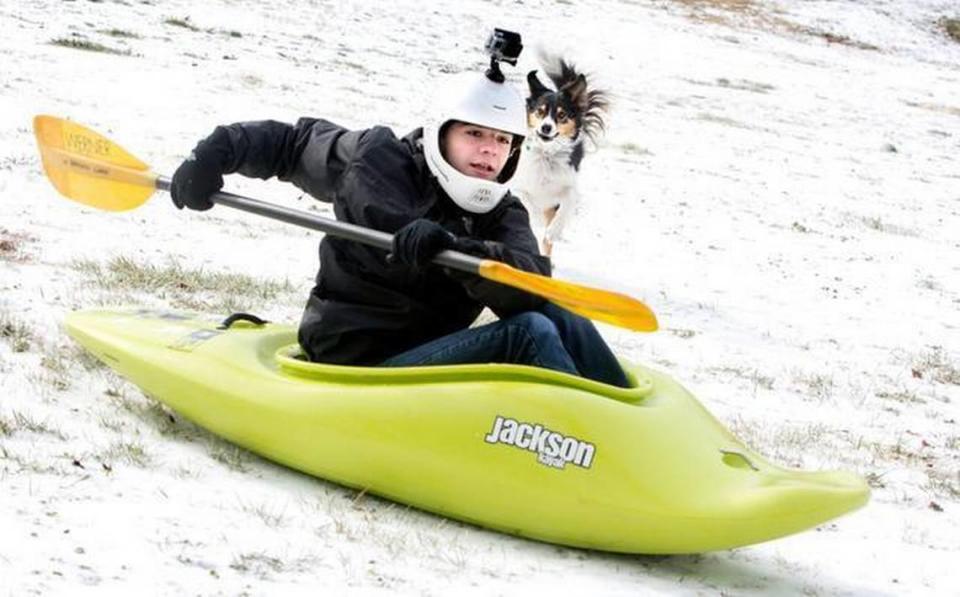 Branson Gray, 15, of Raleigh, uses his kayak for sledding on the Dorothea Dix campus with his dog April at his side on Tuesday, February 17, 2015.