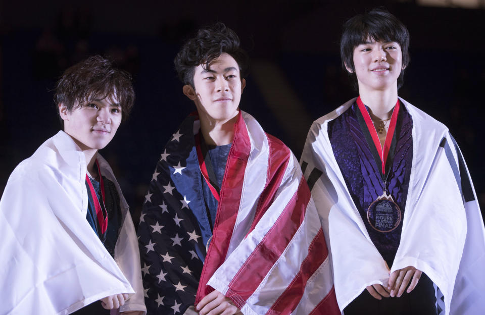 Nathan Chen, of the United States, center, celebrates his gold medal with silver medalist Shoma Uno, of Japan, left, and bronze medalist Jun-hwan Cha, of South Korea, right, following the men's free skate at the figure skating's Grand Prix Final in Vancouver, Friday, Dec. 7, 2018. (Jonathan Hayward/The Canadian Press via AP)