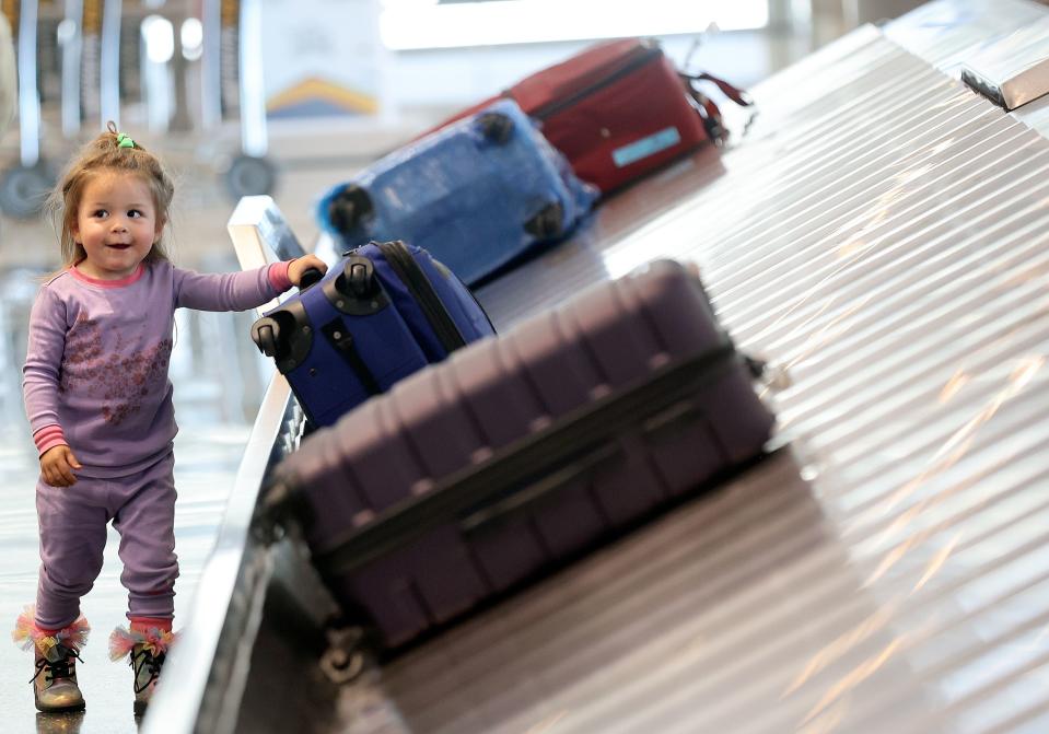 Rozlind Rindlesbach, 2, tries to help pull luggage off the carouse at Salt Lake City International Airport in Salt Lake City on Tuesday, Oct. 31, 2023. | Kristin Murphy, Deseret News