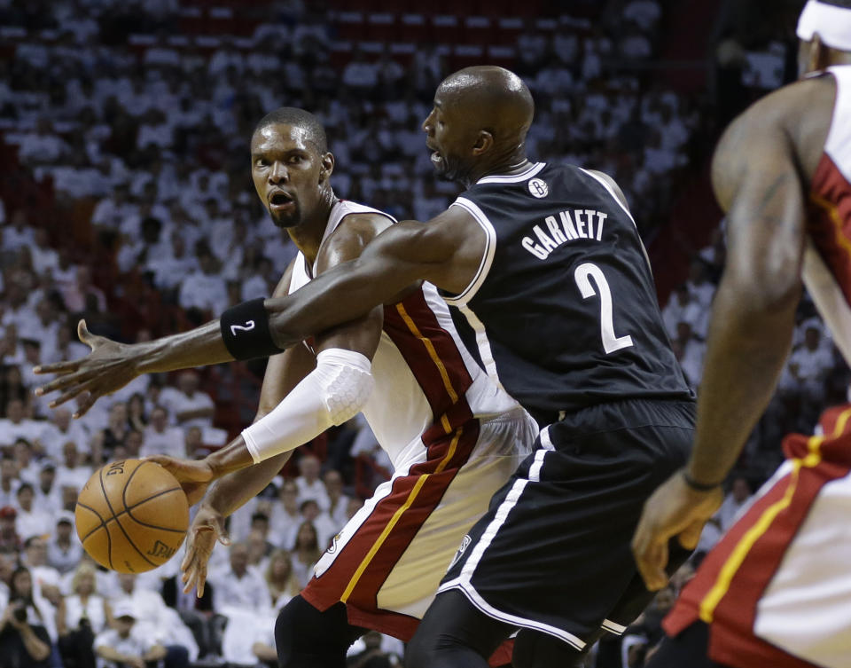 Miami Heat's Chris Bosh, left, passes as Brooklyn Nets' Kevin Garnett (2) defends in the first half of Game 1 in an Eastern Conference semifinal basketball game, Tuesday, May 6, 2014, in Miami. The Heat defeated the Nets 107-86. Bosh scored 15 points and grabbed 11 rebounds. (AP Photo/Lynne Sladky)