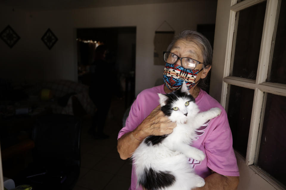 Marta Rosales holds her cat as she looks out from her house Thursday, July 23, 2020, in Brawley, Calif. Rosales stays home as much as possible to keep healthy. But with little income, the family has had to rely on food donations to get by. (AP Photo/Gregory Bull)