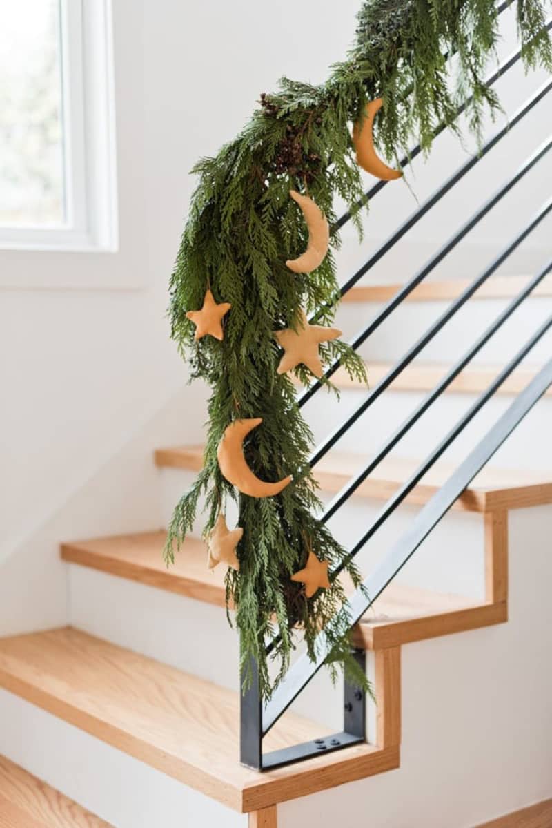 Staircase banister decorated with winter greenery and plus moon and star ornaments