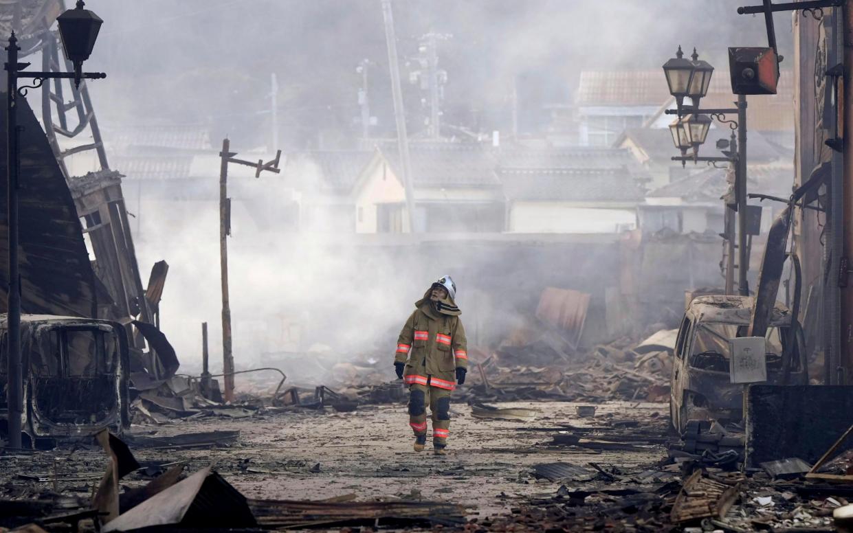 A firefighter walks through the rubble and wreckage of a burnt-out marketplace after an earthquake hit the city of Wajima, in Japan