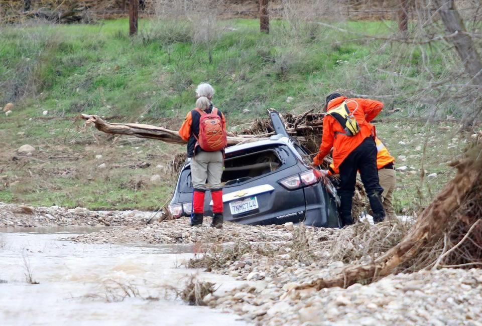Searchers examine the car that was inundated by floodwaters in San Marcos Creek on Monday, Jan. 9, 2023, before 5-year-old Kyle Doan was swept away by floodwaters in San Miguel.