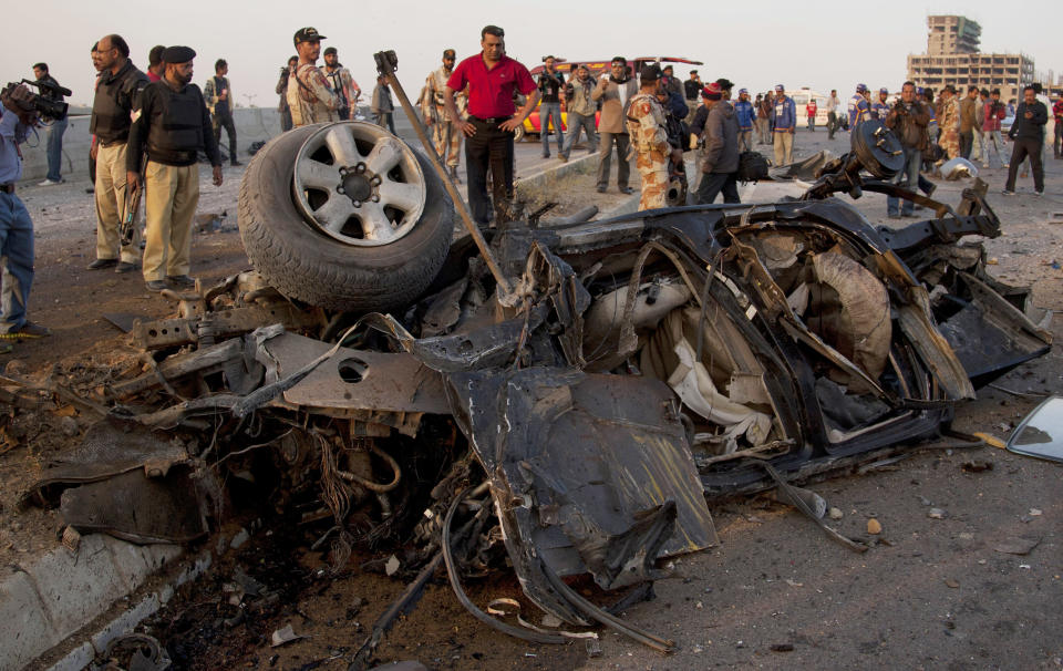 Pakistani investigators look at a vehicle destroyed by a bombing in Karachi, Pakistan, Thursday, Jan. 9, 2014. Police said a car bomb has killed a senior police investigator known for arresting dozens of Pakistani Taliban, as well as two other officers. (AP Photo/Shakil Adil)