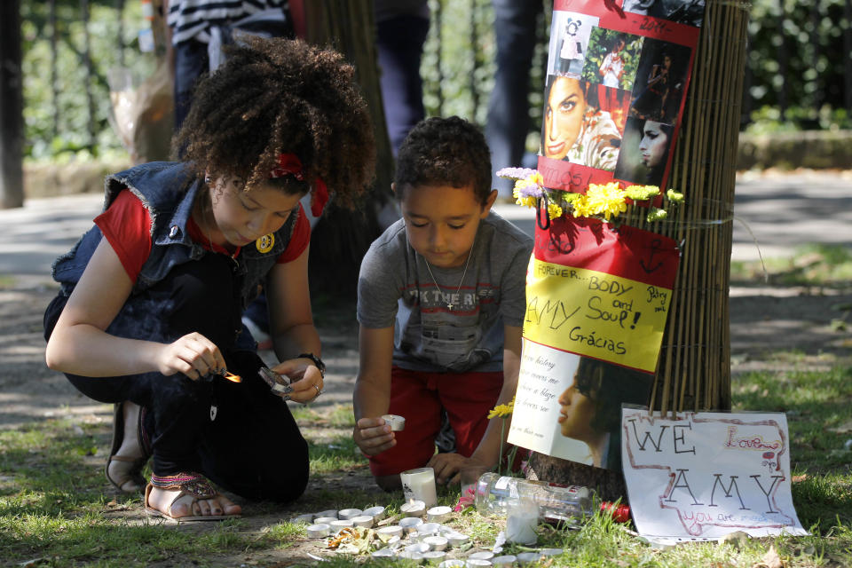 Young fans of British singer songwriter Amy Winehouse light candles for her outside her house in London on the first anniversary of her death, Monday, July 23, 2012. (AP Photo/Sang Tan)