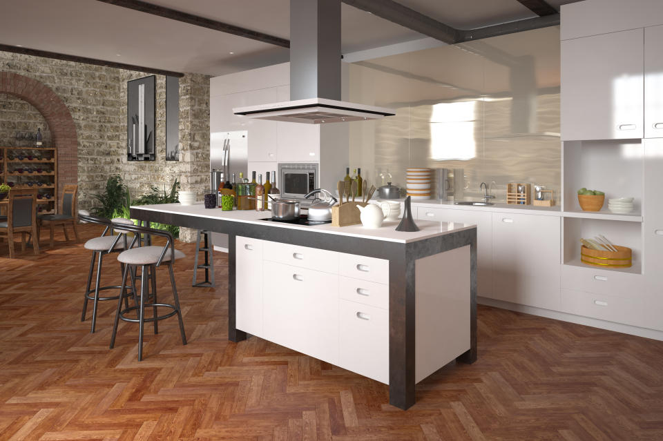 Modern luxury open-plan kitchen with a center island and built in appliances with white decor over a decorative herringbone parquet floor