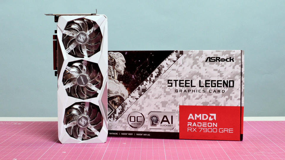 An AMD Radeon RX 7900 GRE from ASRock on a pink desk mat with its retail packaging