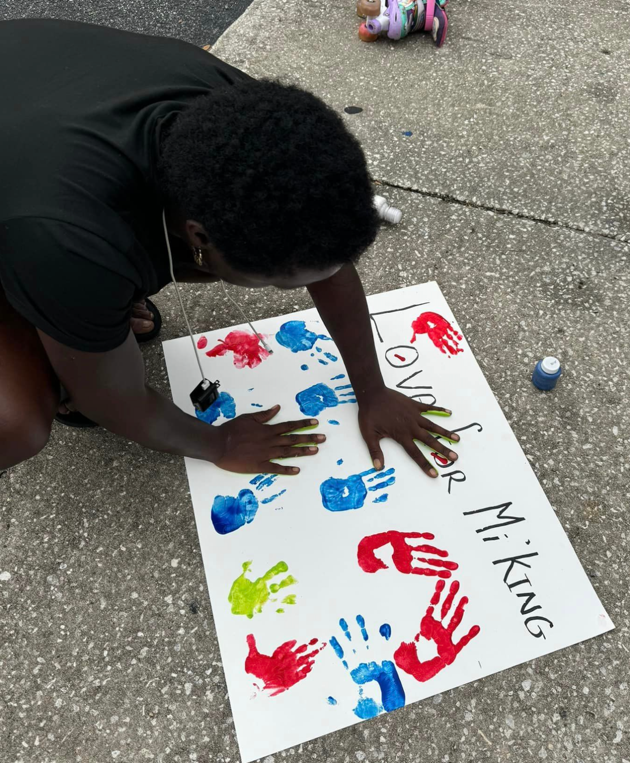 A boy adds his handprints to a poster in honor of Mi'King Sims, 6, who died in a triple shooting at Hollybrook Homes Apartments in Jacksonville on Sept. 27, 2023.