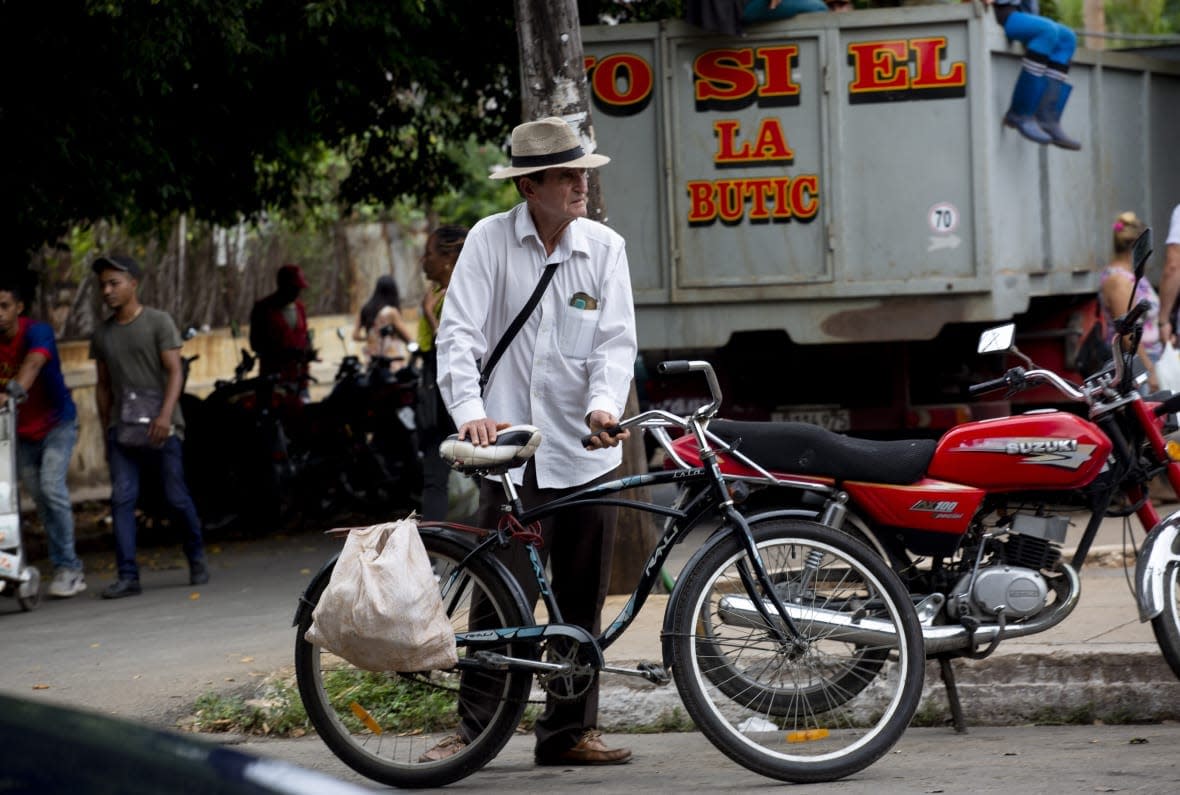 A shopper leaves the 17 and K Market on his bike in Havana, Cuba, Friday, Dec. 23, 2022. In October, the Cuban government reported that inflation had risen 40% over the past year and had a significant impact on the purchasing power for many on the island. (AP Photo/Ismael Francisco)