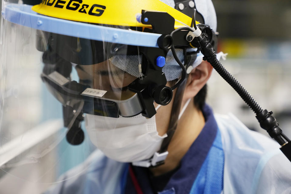 A lab technician wears a pair of smart glasses as he demonstrates a part of a process to measure levels of tritium in water samples at one of the two laboratories at the Fukushima Daiichi nuclear power plant, run by Tokyo Electric Power Company Holdings, in Okuma town, northeastern Japan, Thursday, March 3, 2022. TEPCO and government officials say tritium, which is not harmful in small amounts, is inseparable from the water, but all other 63 radioactive isotopes selected for treatment can be reduced to safe levels, tested and further diluted by seawater before release. (AP Photo/Hiro Komae)