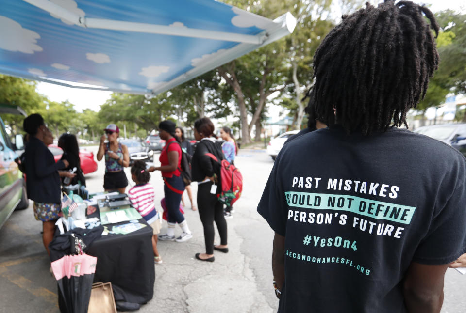 FILE - In this Oct. 22, 2018 file photo, people gather around the Ben & Jerry's "Yes on 4" truck as they learn about Amendment 4 and eat free ice cream at Charles Hadley Park in Miami. With a single vote Tuesday, Nov. 6, Florida added 1.4 million possible voters to the rolls when it passed Amendment 4, which said that most felons will automatically have their voting rights restored when they complete their sentences and probation. (AP Photo/Wilfredo Lee, File)