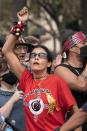 A climate activist cheers on their peers engaged in an act of civil disobedience by blocking an intersection, during a climate change protest including indigenous and youth activists, Friday, Oct. 15, 2021, by the U.S. Capitol in Washington. (AP Photo/Jacquelyn Martin)