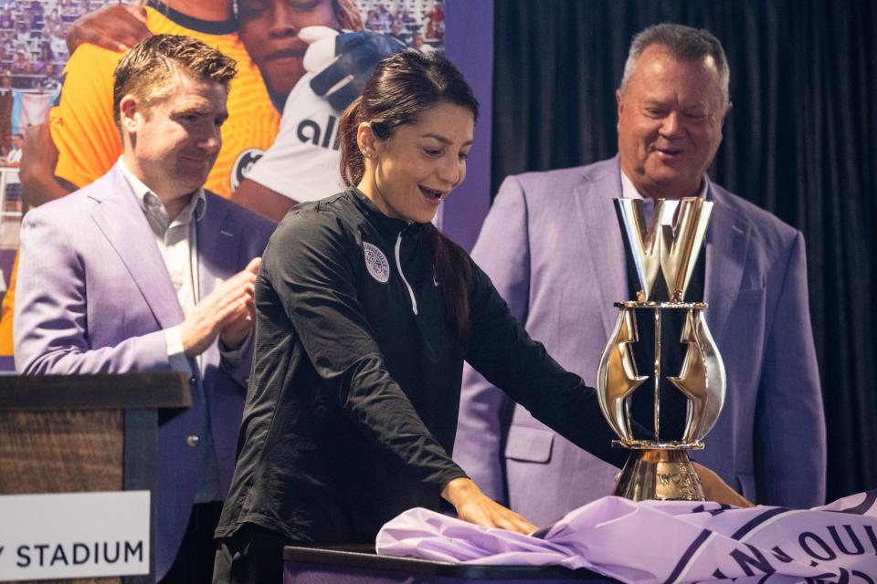 Racing Louisville FC's Nadia Nadim, center, unveils a custom Women's Cup trophy that was presented to the organization at a press conference announcing the 2022 Women's Cup will be held at Lynn Family Stadium on Monday morning. April 12, 2022