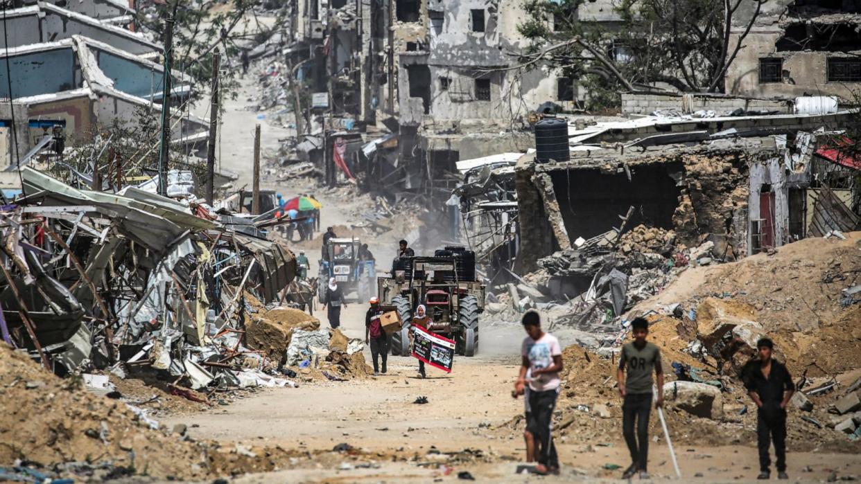 PHOTO: A tractor pulling a cart loaded with cisterns moves past destroyed buildings in Khan Yunis in the southern Gaza Strip, Apr. 22, 2024. (AFP via Getty Images)