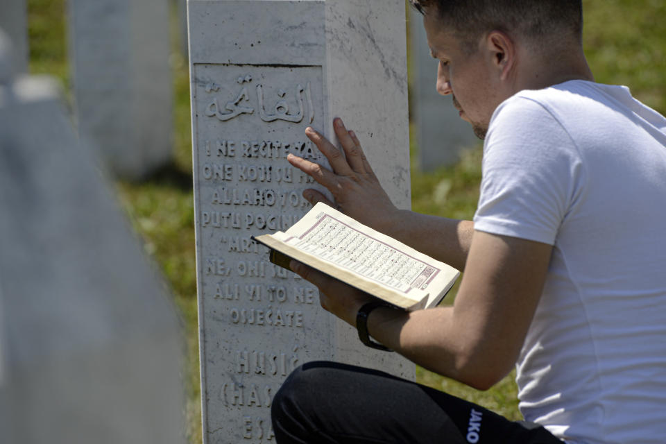 A man prays sitting between grave stones in Potocari, near Srebrenica, Bosnia, Saturday, July 11, 2020. Mourners converged on the eastern Bosnian town of Srebrenica for the 25th anniversary of the country's worst carnage during the 1992-95 war and the only crime in Europe since World War II that has been declared a genocide. (AP Photo/Kemal Softic)