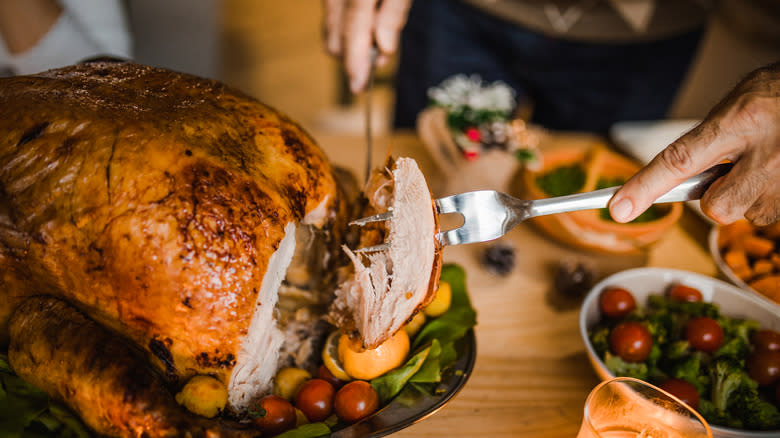 person carving turkey at table 