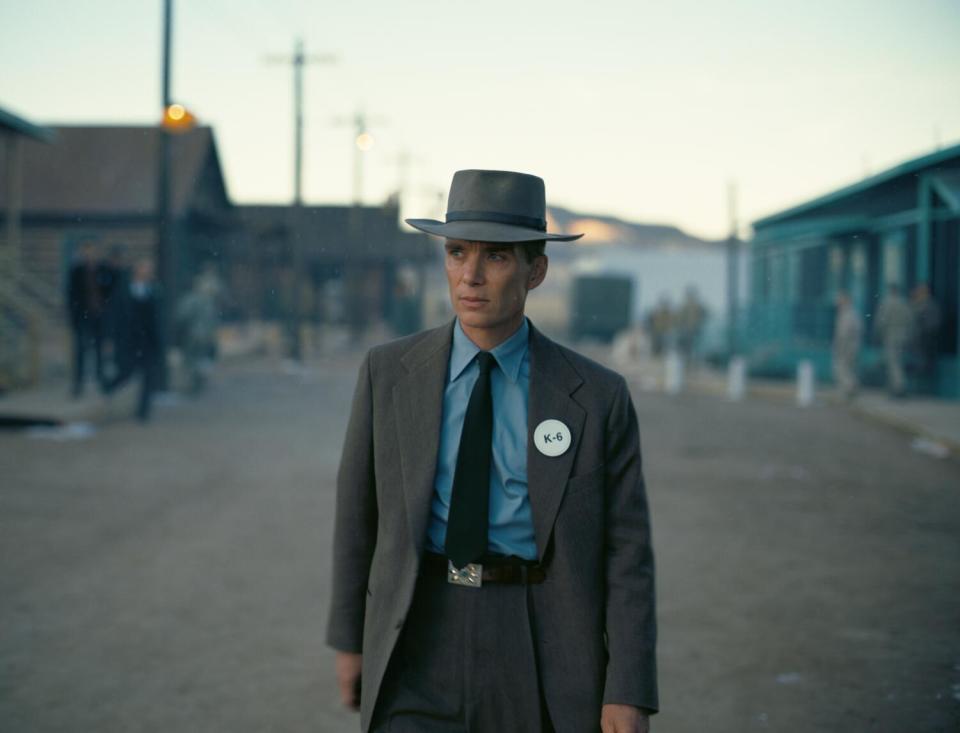 A man in 1940s clothing and hat walks down a dusty street in "Oppenheimer."