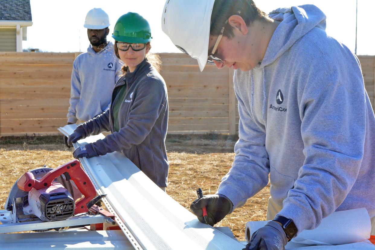 Kenyon Wilson and Hanna Schechter hold a piece of vinyl siding steady while Dylan Aponte draws a cut line to go around a window at a Habitat for Humanity home under construction in the organization's Boone Prairie Subdivision in the 3900 block of Brown Station Road. They are AmeriCorps service workers in Columbia through Dec. 18 aiding Habitat for Humanity and Central Pantry of the Food Bank of Central and Northeast Missouri.