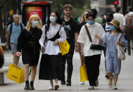 Shoppers wear face coverings to protect themselves from COVID-19 as they walk along Oxford Street in London, Friday, July 24, 2020. New rules on wearing masks in England have come into force, with people going to shops, banks and supermarkets now required to wear face coverings. Police can hand out fines of 100 pounds ($127) if people refuse, but authorities are hoping that peer pressure will prompt compliance. (AP Photo/Frank Augstein)