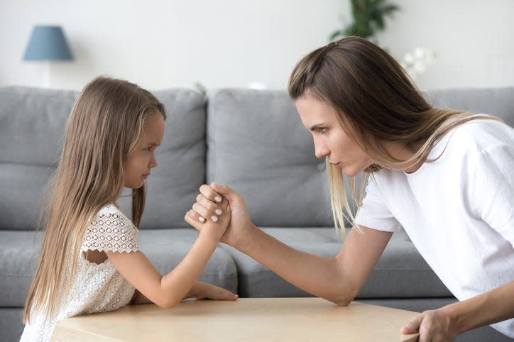 Mom and kid daughter arm wrestling.