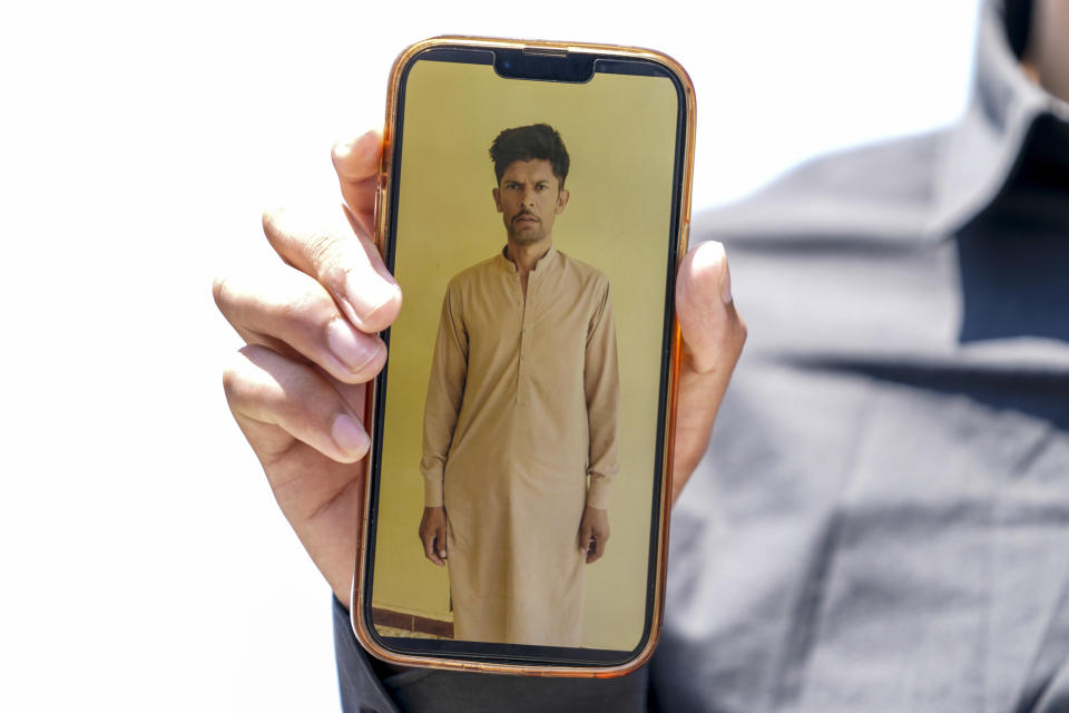 Zohaib Shamraiz holds up a photograph of his missing uncle, 40 year old Nadeem Muhamm, outside a migrant camp in Malakasa north of Athens, on Monday, June 19, 2023. Hundreds of migrants are believed to be missing after a fishing trawler sank off southern Greece last week. (AP Photo/Petros Giannakouris)