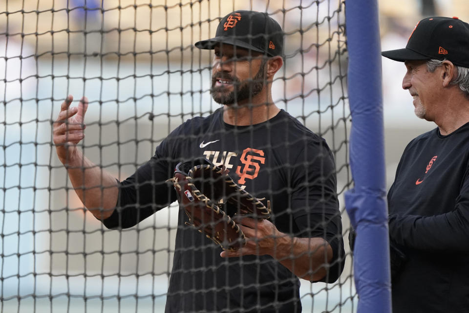 San Francisco Giants manager Gabe Kapler, left, talks with third base coach Ron Wotus, right, before Game 3 of a baseball National League Division Series against the Los Angeles Dodgers, Monday, Oct. 11, 2021, in Los Angeles. (AP Photo/Marcio Sanchez)