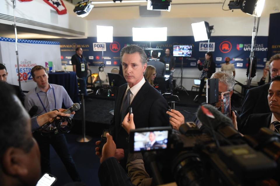 Newsom surrounded by cameras, lights and journalists