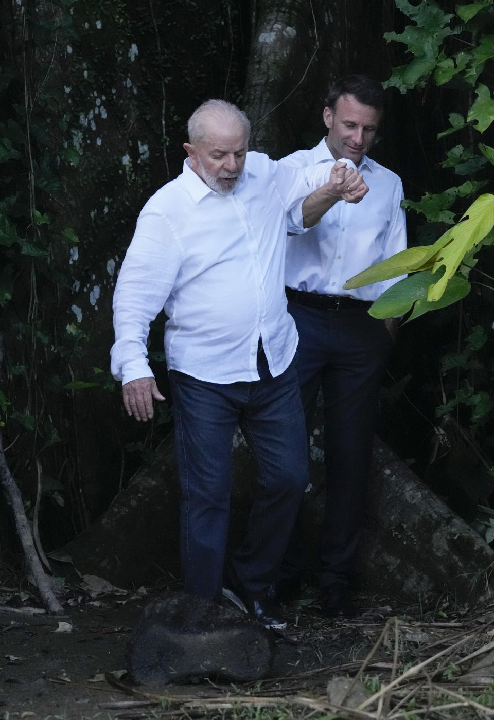 Brazil's President Luiz Inacio Lula da Silva, left, leads French President Emmanuel Macron through an island path as they arrive in Combu, near Belem, Para state, Brazil, Tuesday, March 26, 2024. Macron is on a three-day official visit to Brazil. (AP Photo/Eraldo Peres)