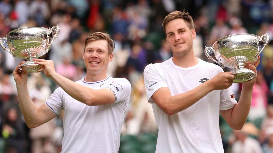 Henry Patten and Harri Heliovaara hold their Wimbledon trophies