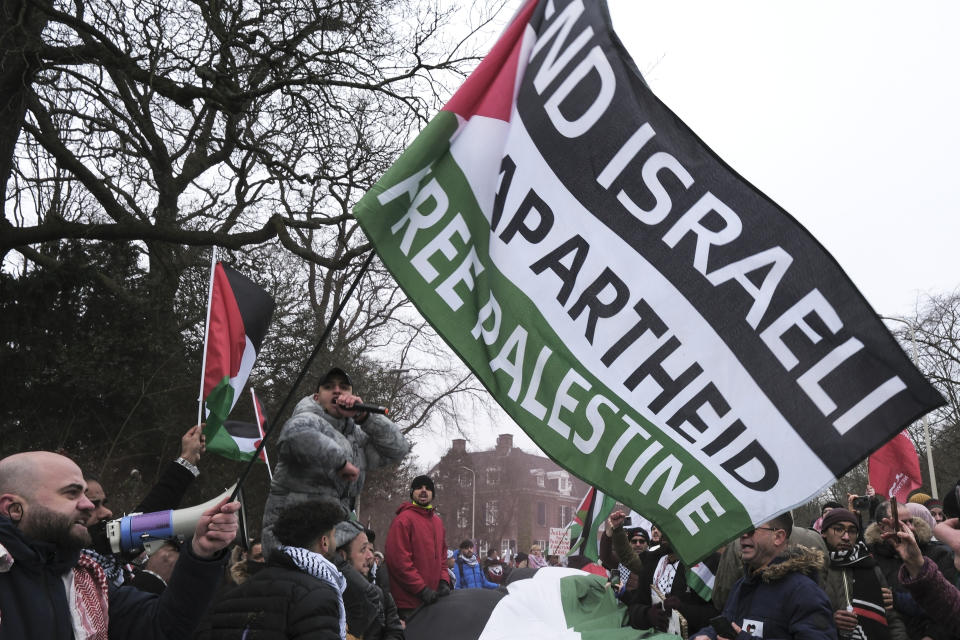 Protestors wave Palestinian flags during a demonstration march outside the International Court of Justice in The Hague, Netherlands, Thursday, Jan. 11, 2024. The United Nations' top court opens hearings Thursday into South Africa's allegation that Israel's war with Hamas amounts to genocide against Palestinians, a claim that Israel strongly denies. (AP Photo/Patrick Post)