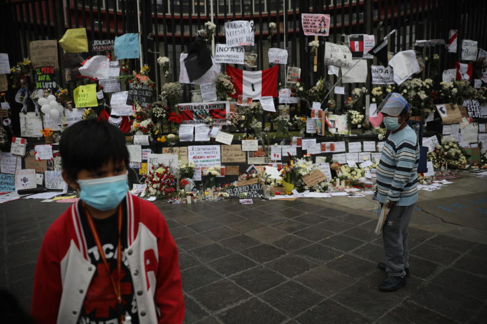 People wearing masks amid the COVID-19 pandemic visit a memorial where two people died during Nov. 14 protests against lawmakers' removal of President Martin Vizcarra, near Congress in Lima, Peru, Monday, Nov. 16, 2020. Peru's political turmoil took a turn Sunday when interim leader Manuel Merino quit and Congress couldn't decide on his replacement, leaving the nation without a president and in crisis less than a week after legislators removed Vizcarra. (AP Photo/Rodrigo Abd)