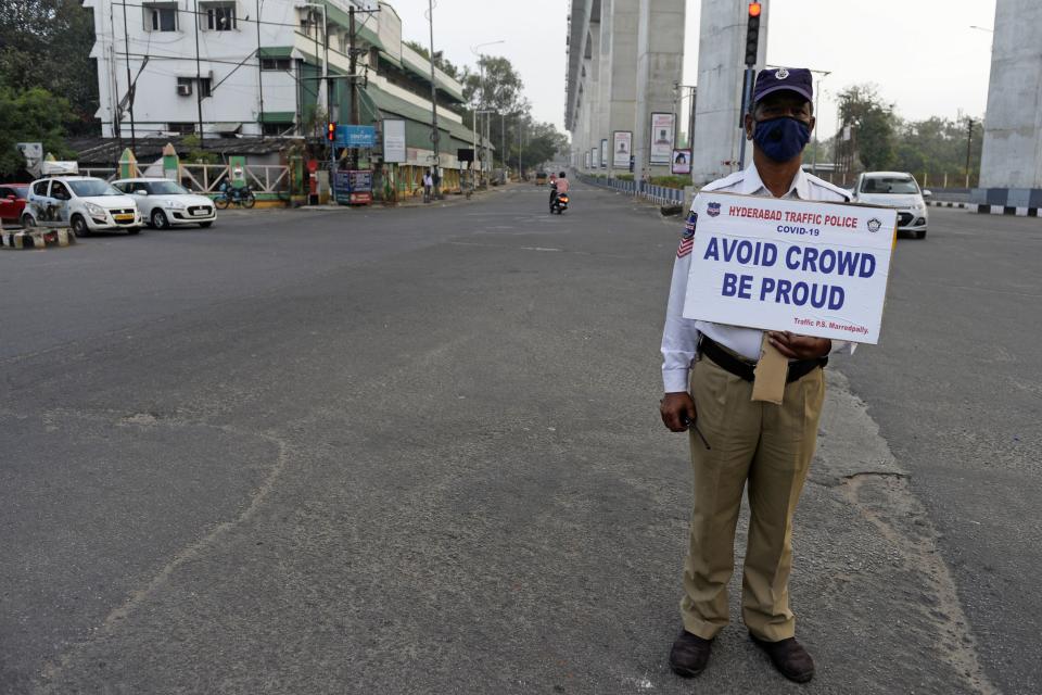 A traffic police personnel holds a placard as he stands guard on a deserted road junction during a one-day Janata (civil) curfew imposed amid concerns over the spread of the COVID-19 novel coronavirus, in Secunderabad, the twin city of Hyderabad, on March 22, 2020. (Photo by NOAH SEELAM / AFP) (Photo by NOAH SEELAM/AFP via Getty Images)