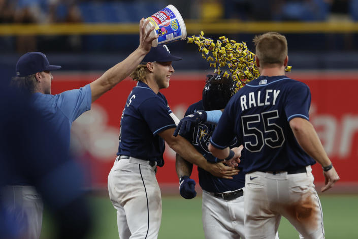 Tampa Bay Rays' Harold Ramirez, second from right, is showered with bubble gum while celebrating with Taylor Walls, second from left, and Luke Raley after the team's win over the Pittsburgh Pirates in 10 innings in a baseball game Friday, June 24, 2022, in St. Petersburg, Fla. (AP Photo/Scott Audette)