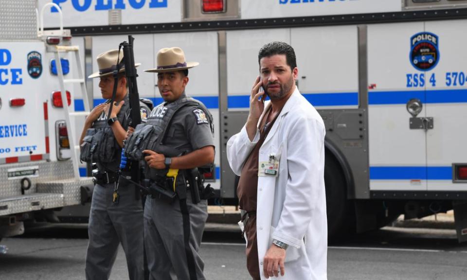 A hospital staff member talks on his phone as he walks past police outside the Bronx Lebanon hospital center.