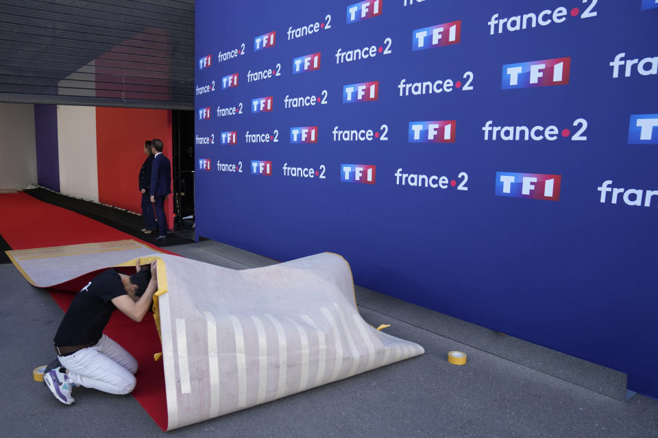 A worker arranges the red carpet at a television recording studio Wednesday, April 20, 2022 in La Plaine-Saint-Denis, outside Paris. In the climax of France's presidential campaign, centrist President Emmanuel Macron and far-right contender Marine Le Pen will meet Wednesday evening in a one-on-one television debate that could prove decisive before Sunday's runoff vote. (AP Photo/Francois Mori)