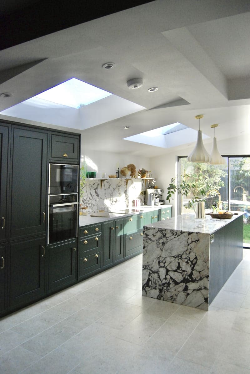 Kitchen with green cabinets, marble island, and dining area.