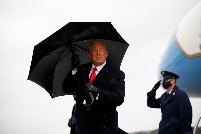 U.S. President Donald Trump holds an umbrella as he arrives for a campaign rally, at Oakland County International Airport