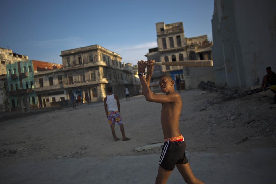 In this April 12, 2014 photo, youngsters play baseball next to rundown buildings in Havana, Cuba. The country lacks around 500,000 units of housing according to the most recent government numbers from 2010. The problem grows each year as more buildings fall further into disrepair, punished year-round by the tropical sun, sea and wind.(AP Photo/Ramon Espinosa)