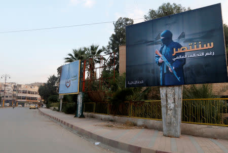 FILE PHOTO - Islamic State billboards are seen along a street in Raqqa, eastern Syria, which is controlled by the Islamic State, October 29, 2014. The billboard (R) reads: "We will win despite the global coalition". REUTERS/Nour Fourat/File Photo