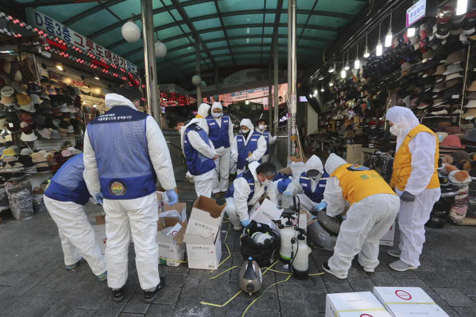 Trabajadores con equipo protector se preparan para rociar con desinfectante el popular mercado de Namdaemun de Seúl el 5 de febtero del 2020, en el marco de esfuerzos para evitar la propagación del coronavirus. (AP Photo/Ahn Young-joon)