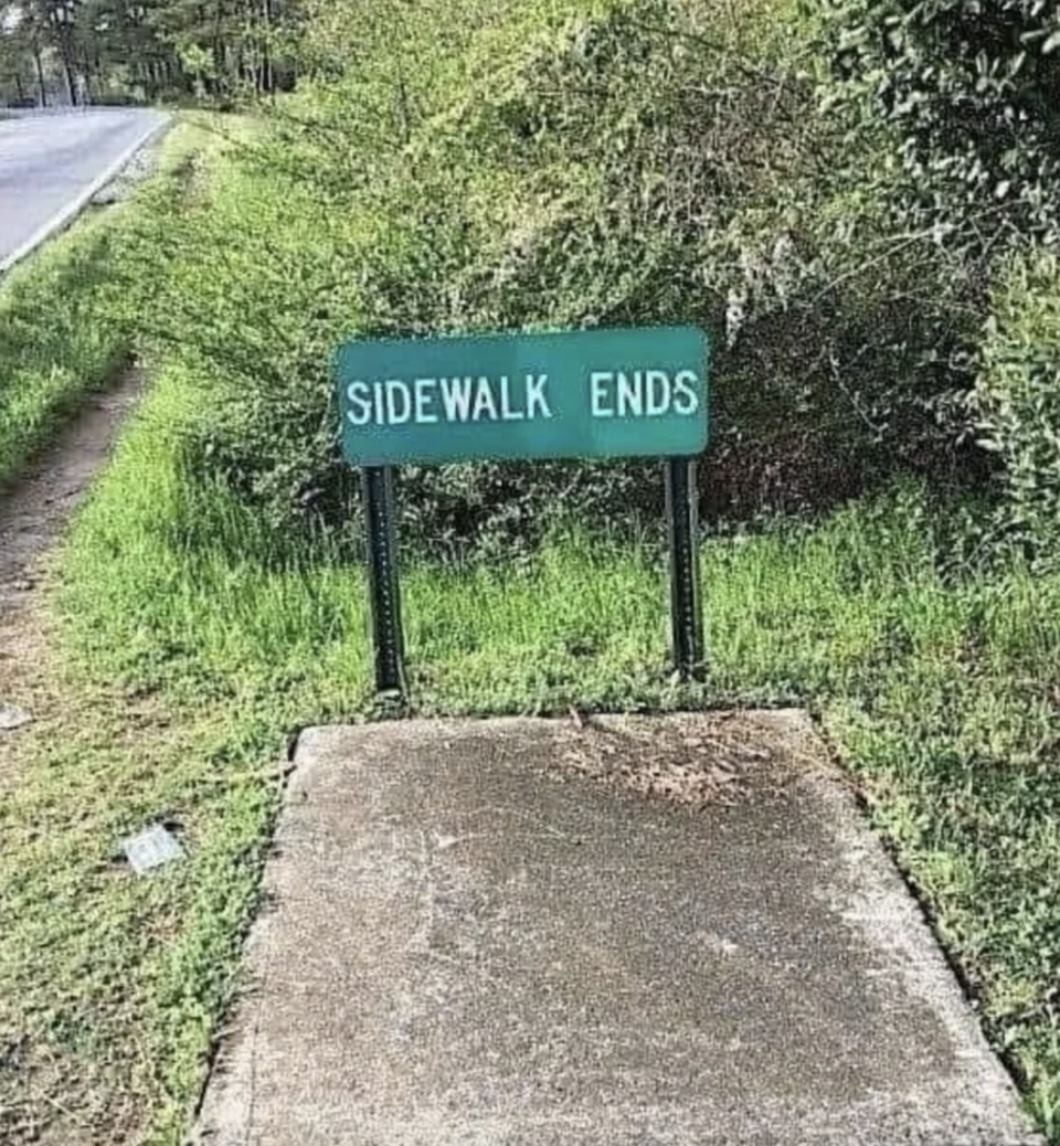 Sign reads "SIDEWALK ENDS" where a concrete sidewalk meets grass