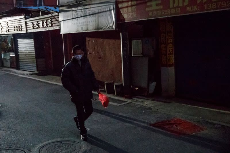 Man wears a face mask in a deserted market alley in Jiujiang