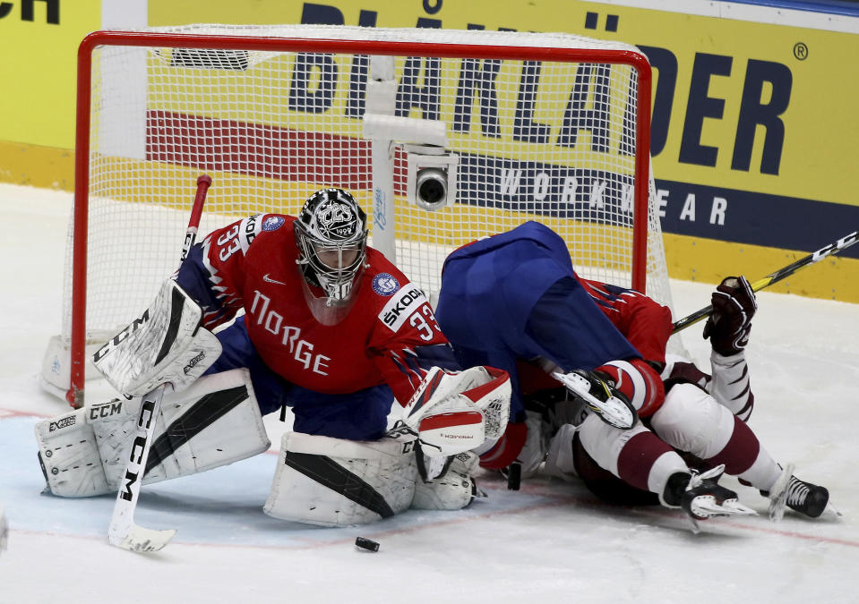 Norway's goalkeeper Henrik Haukeland, left, checks Erlend Lesund and Latvia's Teodors Blugers, right during the Ice Hockey World Championships group B match between Norway and Latvia at the Ondrej Nepela Arena in Bratislava, Slovakia, Tuesday, May 21, 2019. (AP Photo/Ronald Zak)