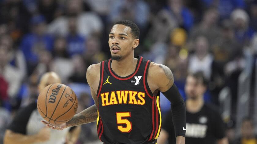 Atlanta Hawks guard Dejounte Murray moves the ball during the first half of an NBA basketball game.