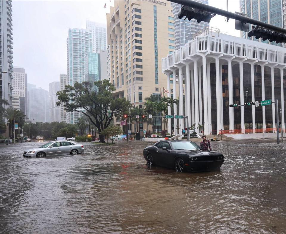 Un conductor de pie junto a su Dodge último modelo después de que el auto quedara inmovilizado cuando la tormenta tropical Eta azotó Miami, dejando a los automovilistas que cruzaban la intersección de SW 13 Street y Brickell Avenue atascados en el agua de las inundaciones debido a las fuertes lluvias del 9 de noviembre de 2020.