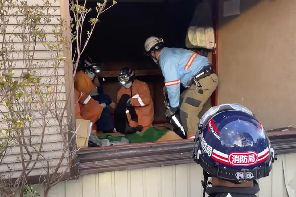 In this image from a video provided by Osaka Municipal Fire Department, a woman, center, who was found trapped under her destroyed house is rescued 72 hours after a strong earthquake in Wajima, Ishikawa prefecture, Japan Thursday, Jan. 4, 2024. The woman was conscious and sent to a hospital, according to Osaka Municipal Fire Department. (Osaka Municipal Fire Department via AP)