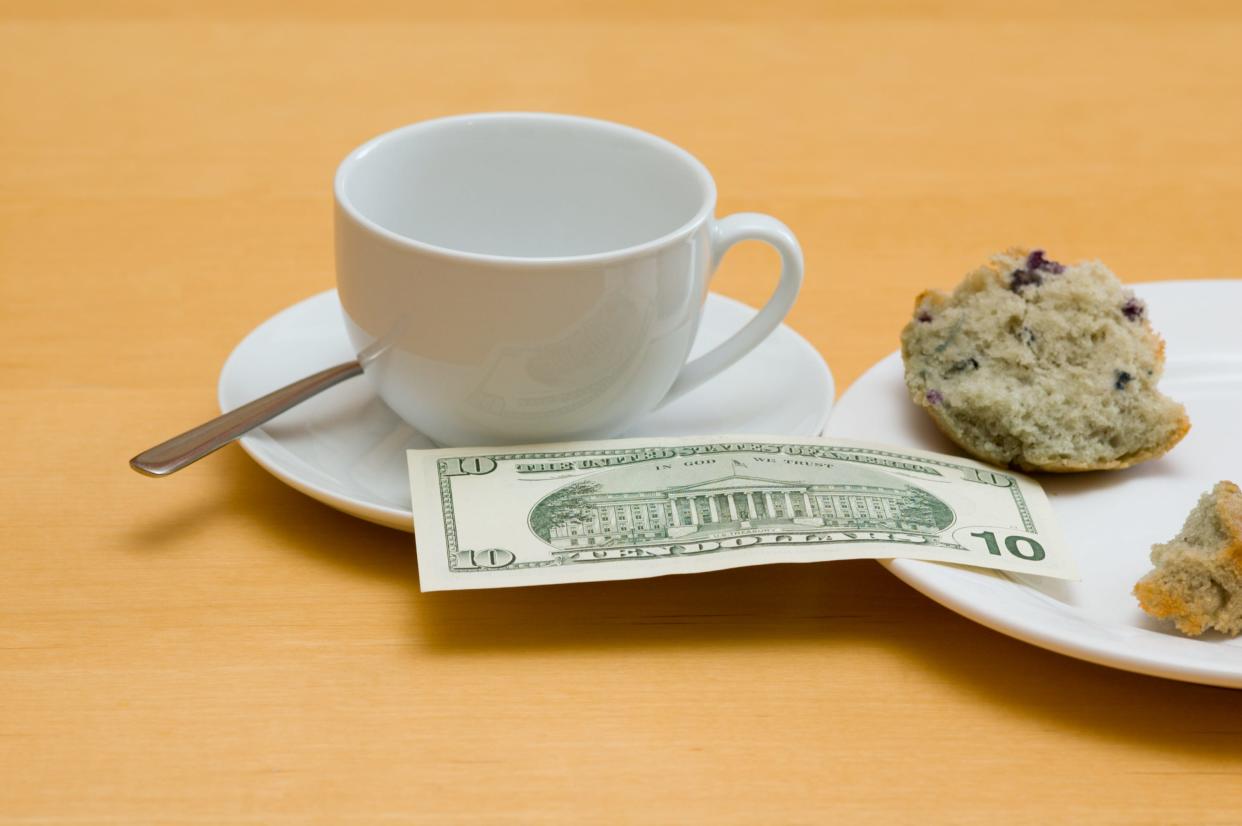A cup, a $10 bill, a muffin broken in half.