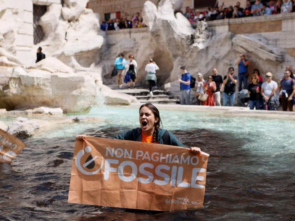 Climate activist holds banner in Trevi Fountain, Rome.