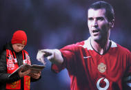 <p>United legend Roy Keane shows a fan the best bit of the matchday programme </p>